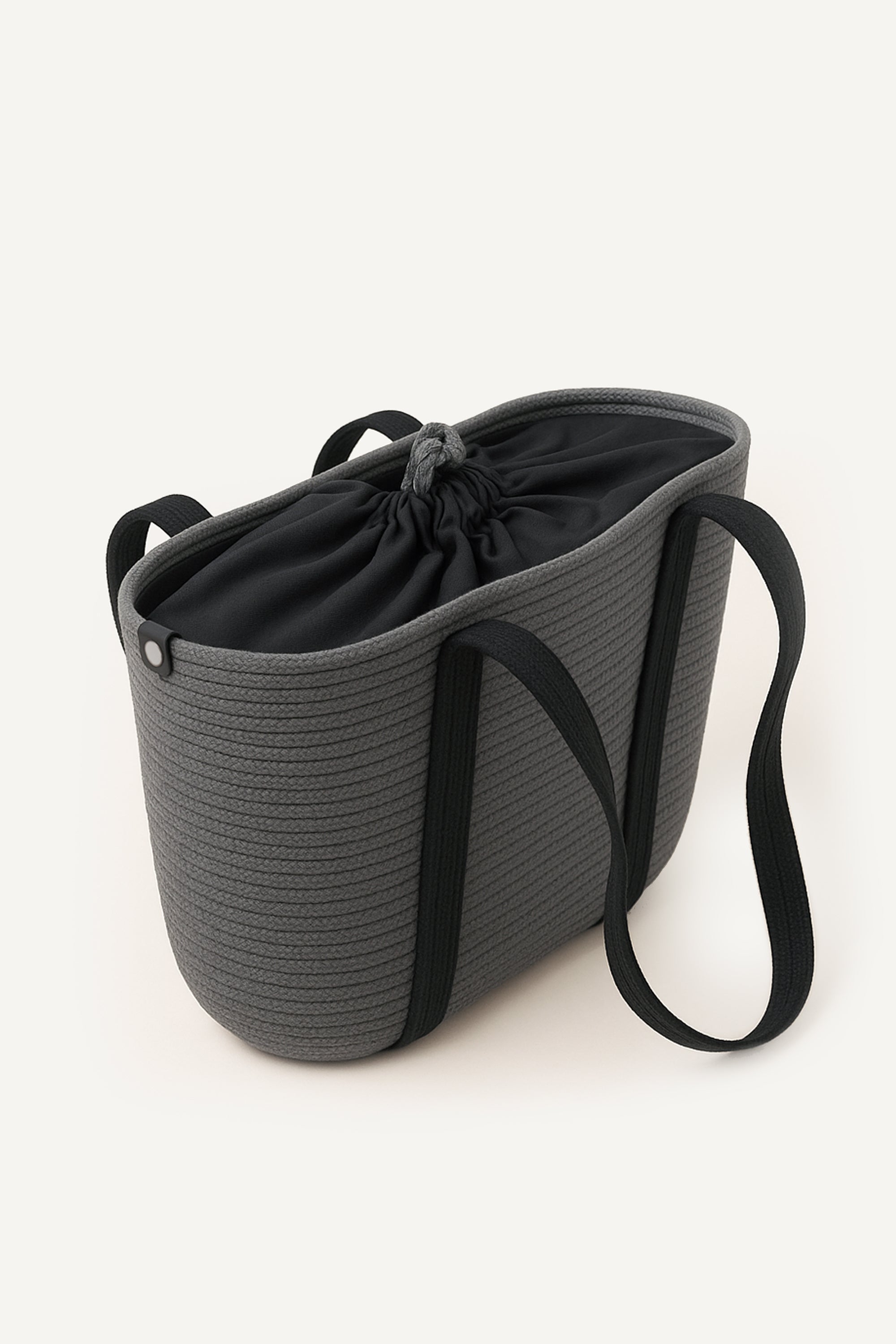 Top view of a gray woven crochet tote bag with black handles on a white background