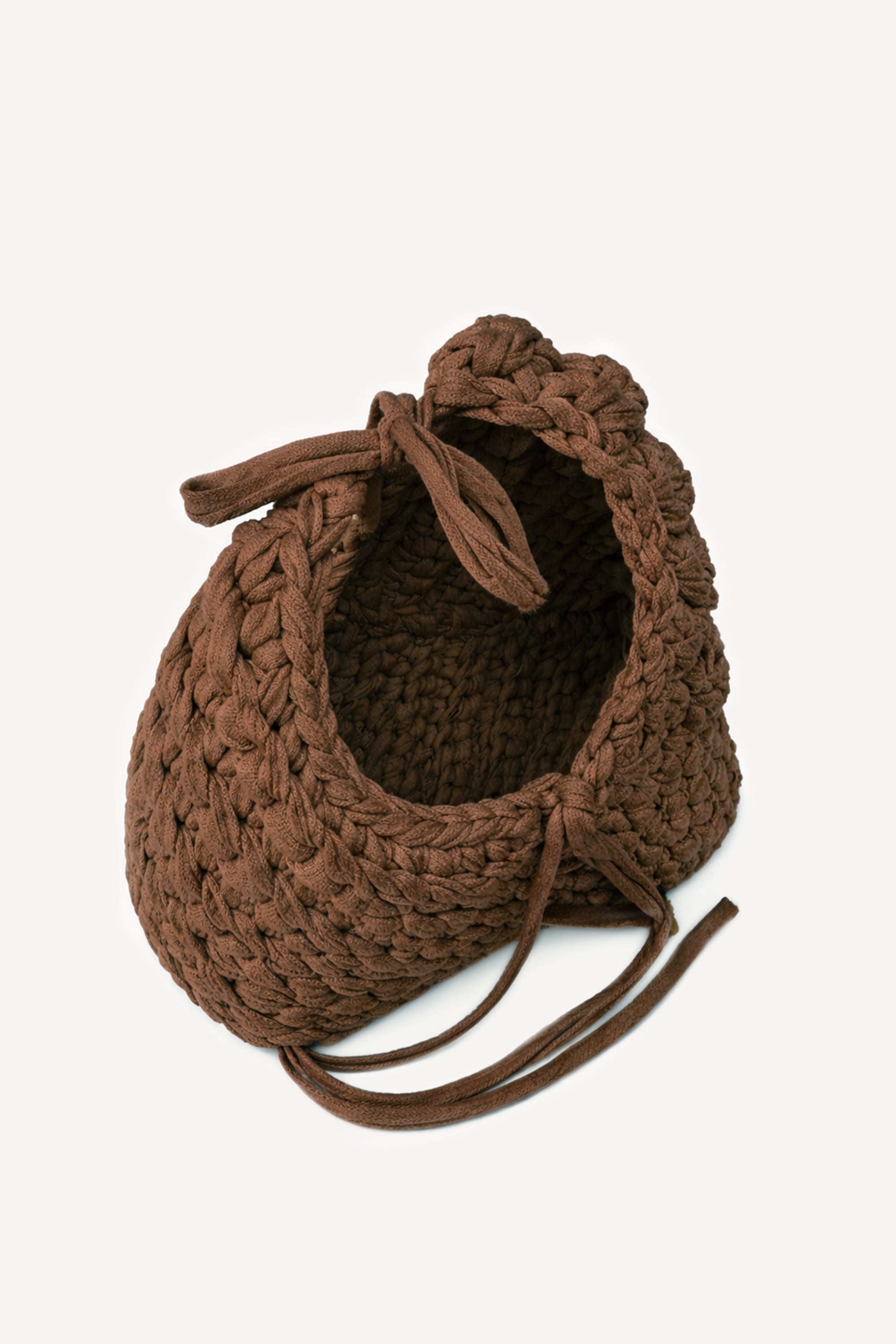 Angled view of Lviv crochet brown woven handbag with tassels on a light beige background