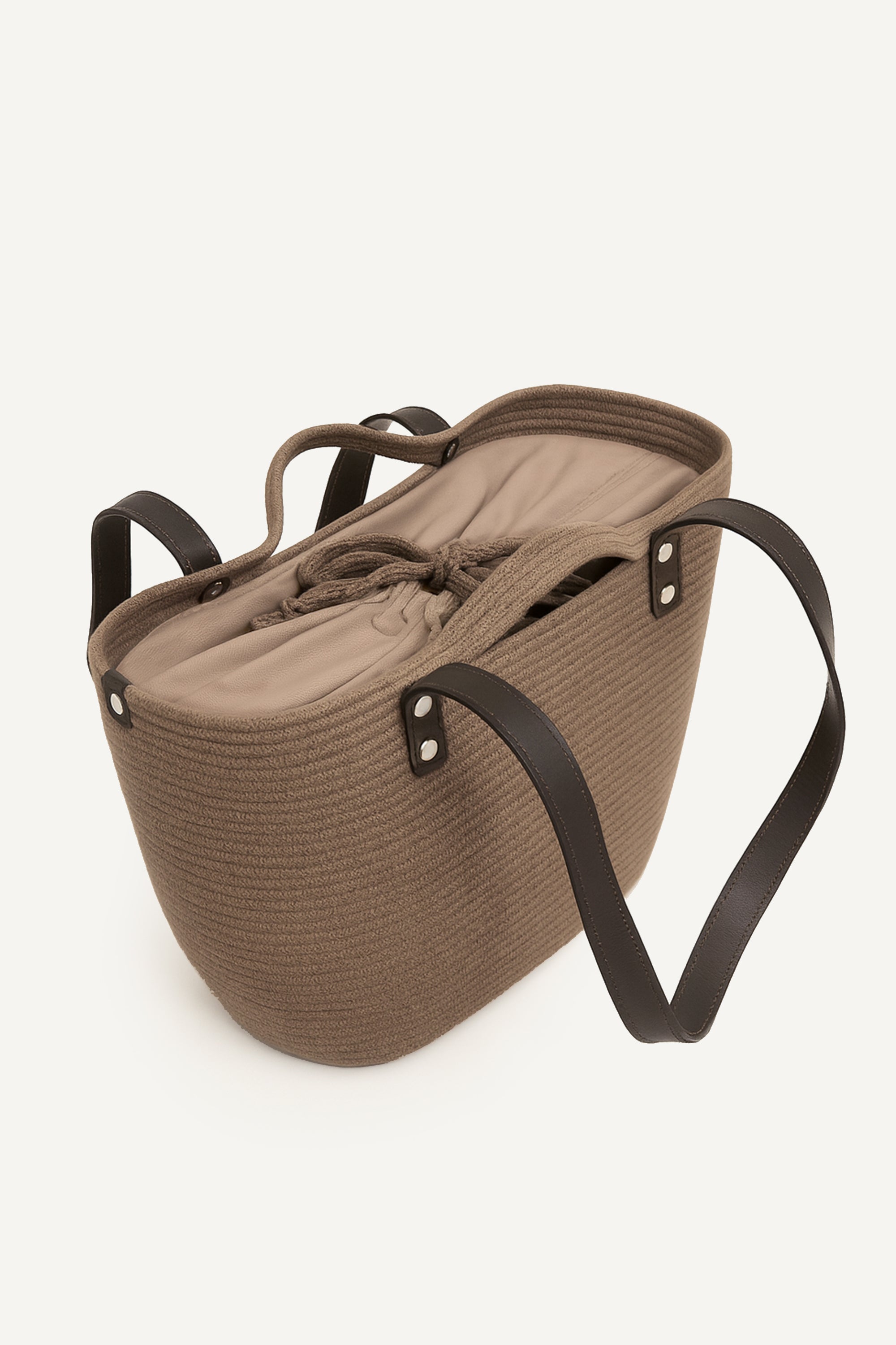 Topside view of the brown woven capri tote bag with leather handles on a white background