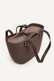 Topside front view of the brown woven capri tote bag with leather handles on a white background