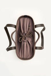 Top view of the brown woven capri tote bag with leather handles on a white background