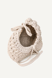Angled view of Lviv crochet beige woven handbag with tassels on a light beige background