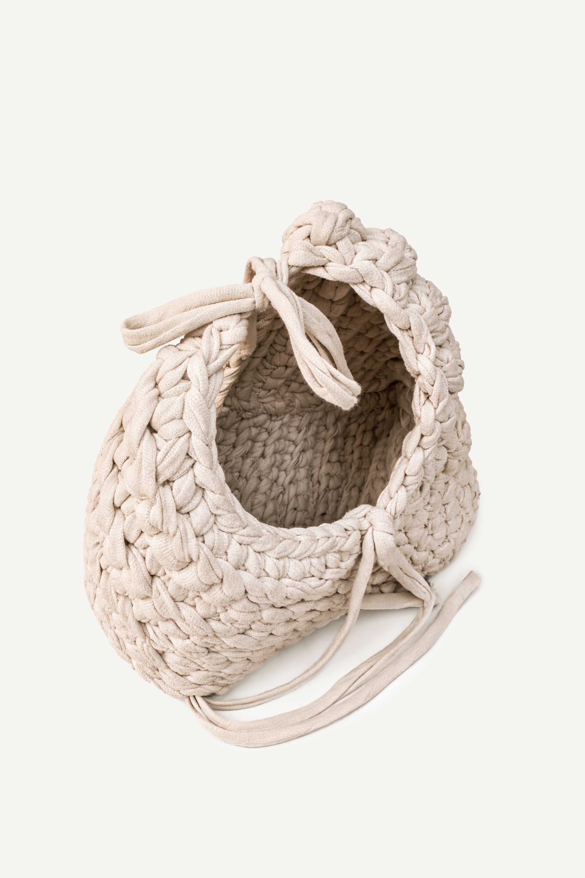 Angled view of Lviv crochet beige woven handbag with tassels on a light beige background
