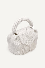 Angled view of the woven white assos crochet top-handle bag with fringe detailing