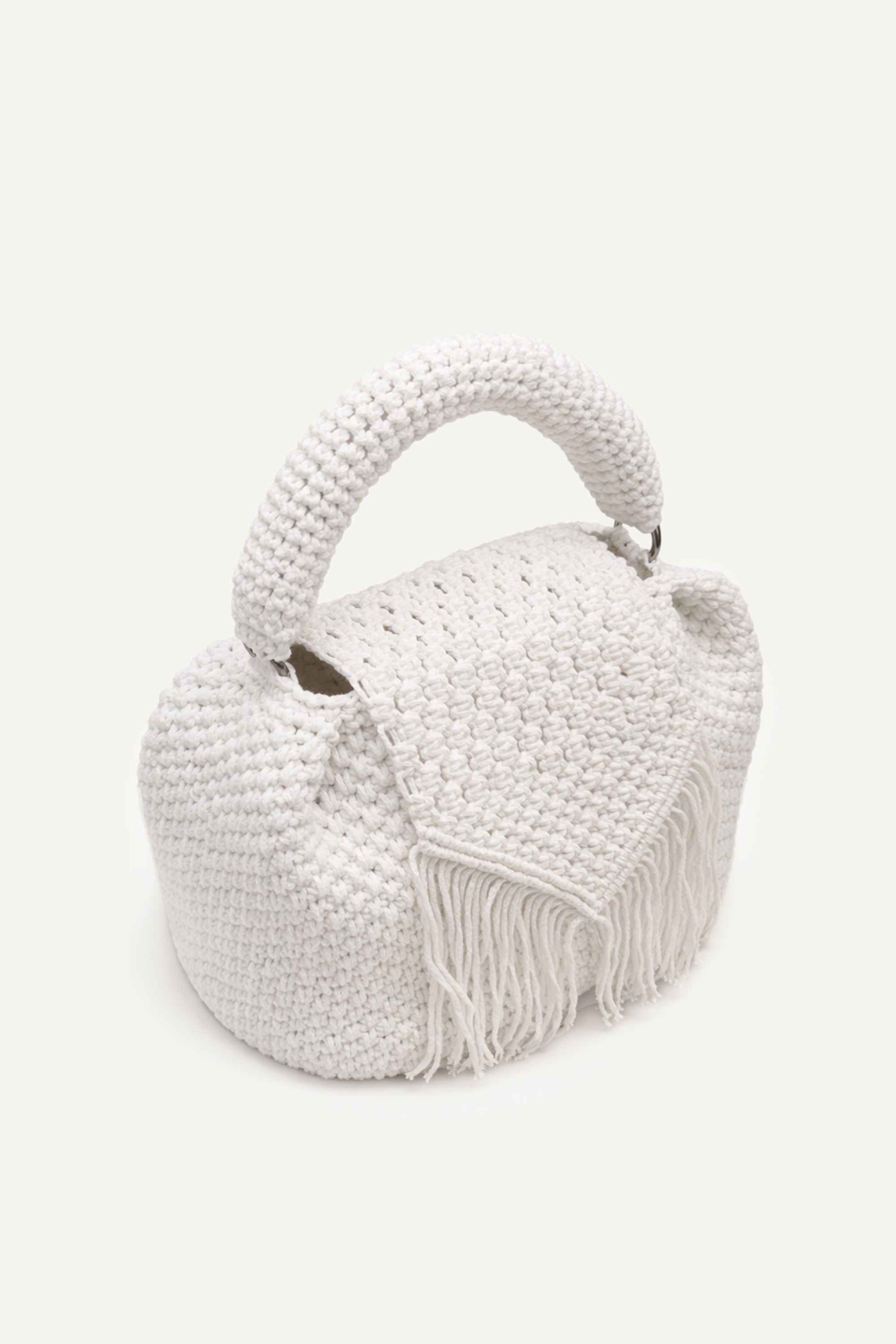Angled view of the woven white assos crochet top-handle bag with fringe detailing
