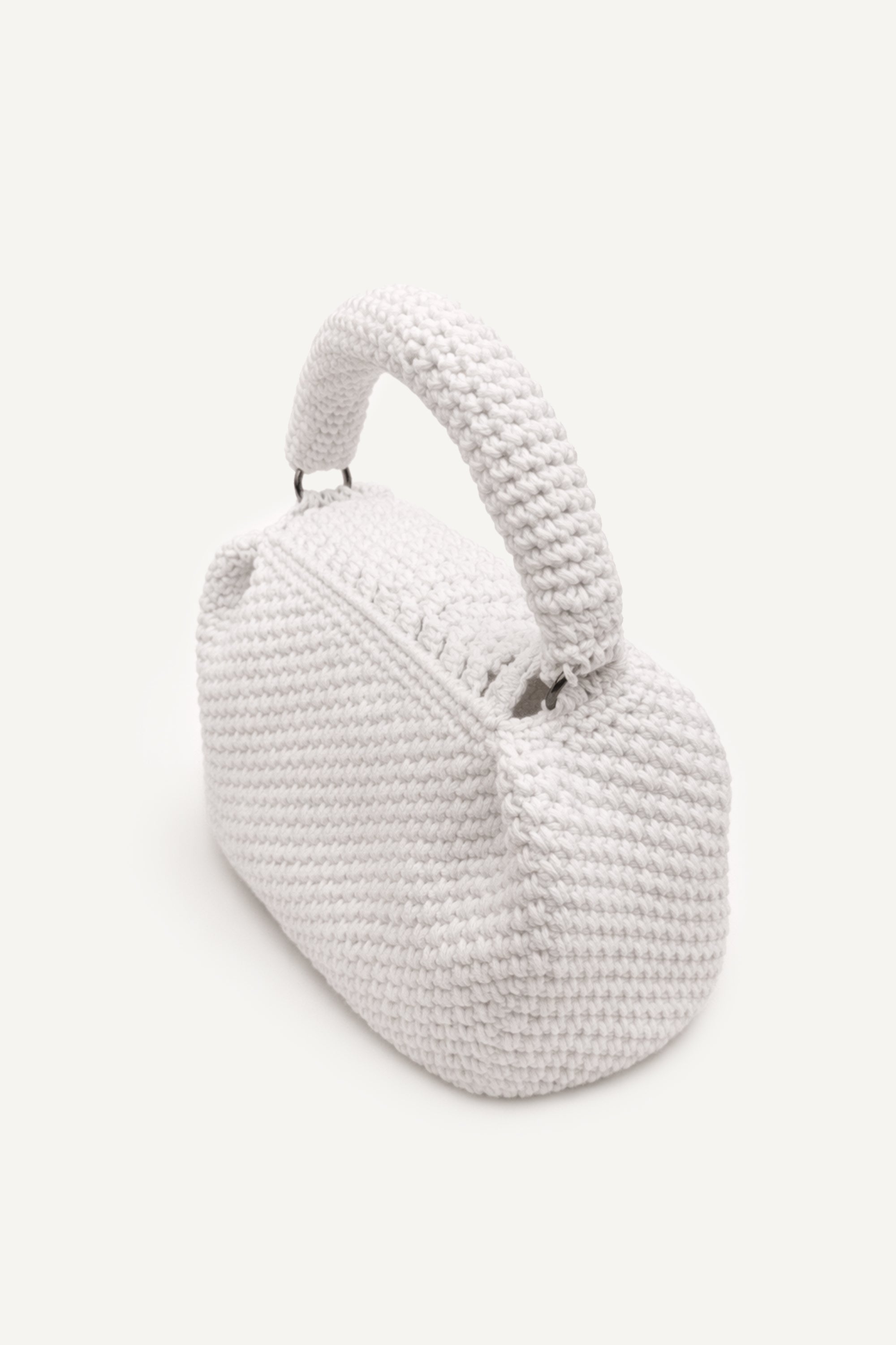 Angled back view of the woven white assos crochet top-handle bag with fringe detailing