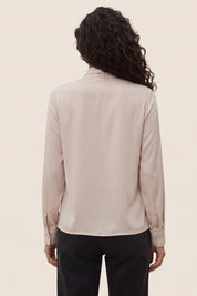 Back view of a woman wearing the beige Charming Blouse by FemeAdor with bowtie detail and flattering drape, ideal for professional and casual styling