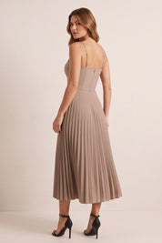 Back view of a woman wearing the beige Eclipse Demi Dress by FemeAdor featuring a structured corset top and a flowing pleated midi skirt perfect for formal and casual events