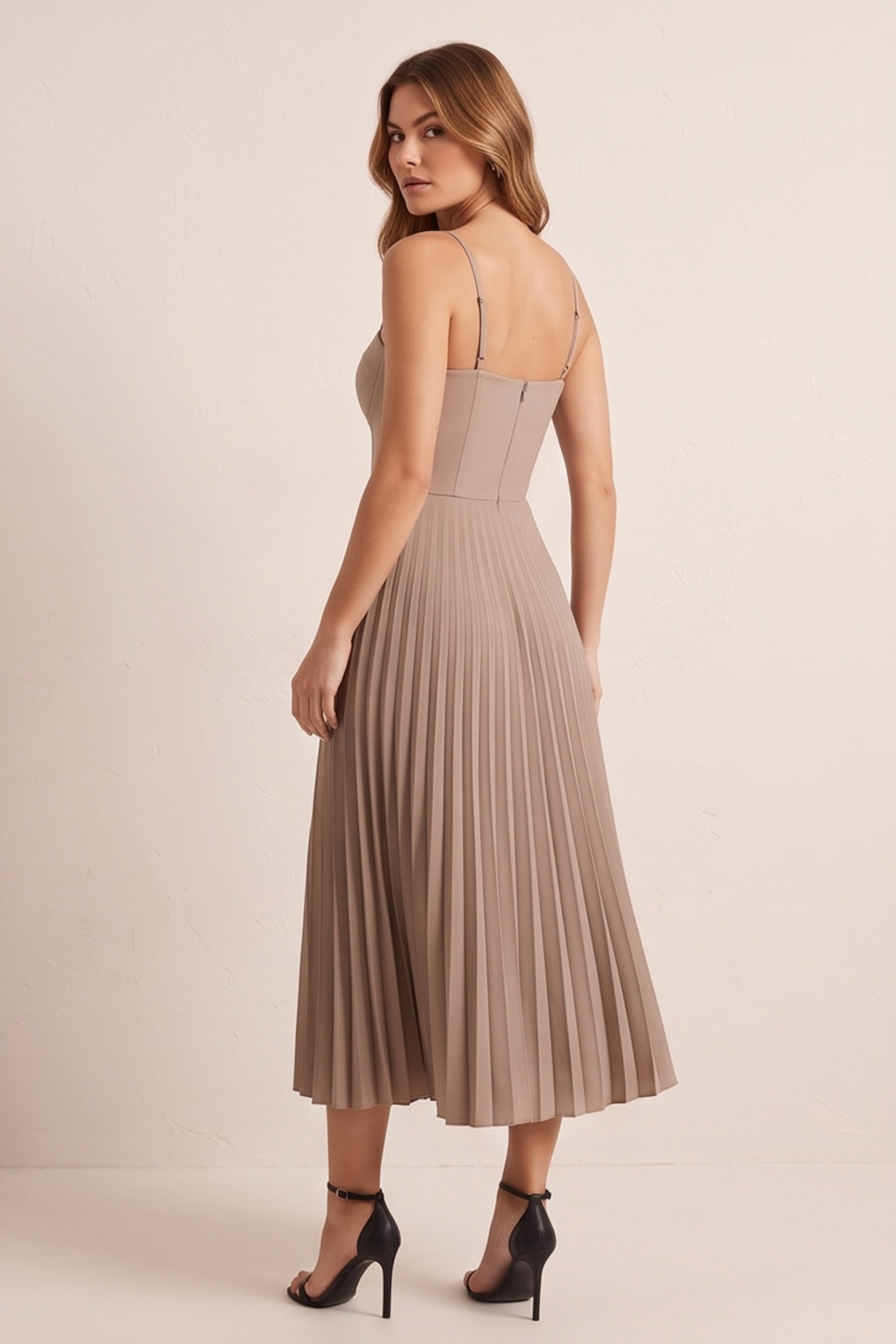 Back view of a woman wearing the beige Eclipse Demi Dress by FemeAdor featuring a structured corset top and a flowing pleated midi skirt perfect for formal and casual events