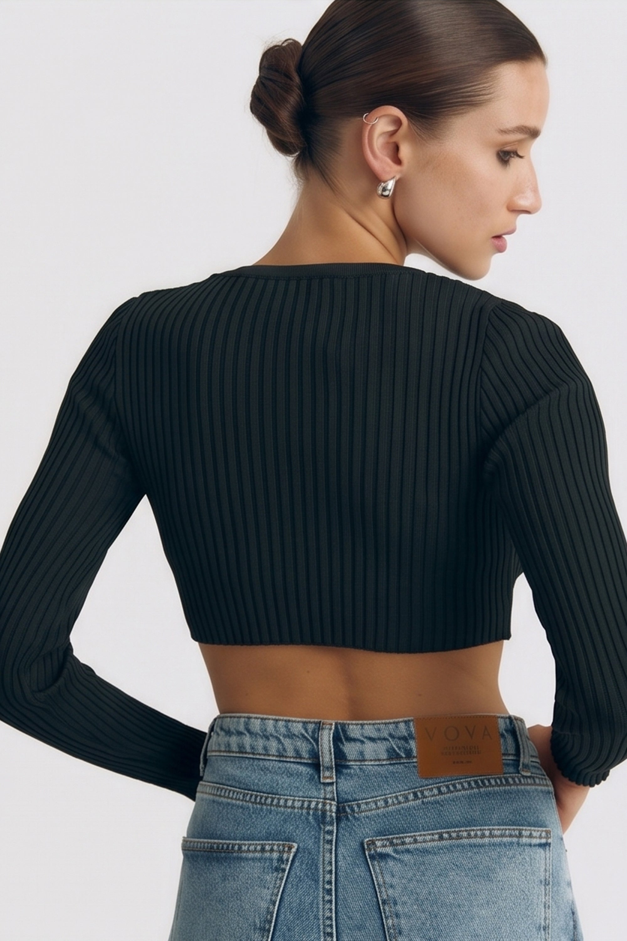 Back view of a woman wearing the black Cropped Longsleeve Top by FemeAdor featuring a flattering cropped cut and a cozy fitted ribbed knit design