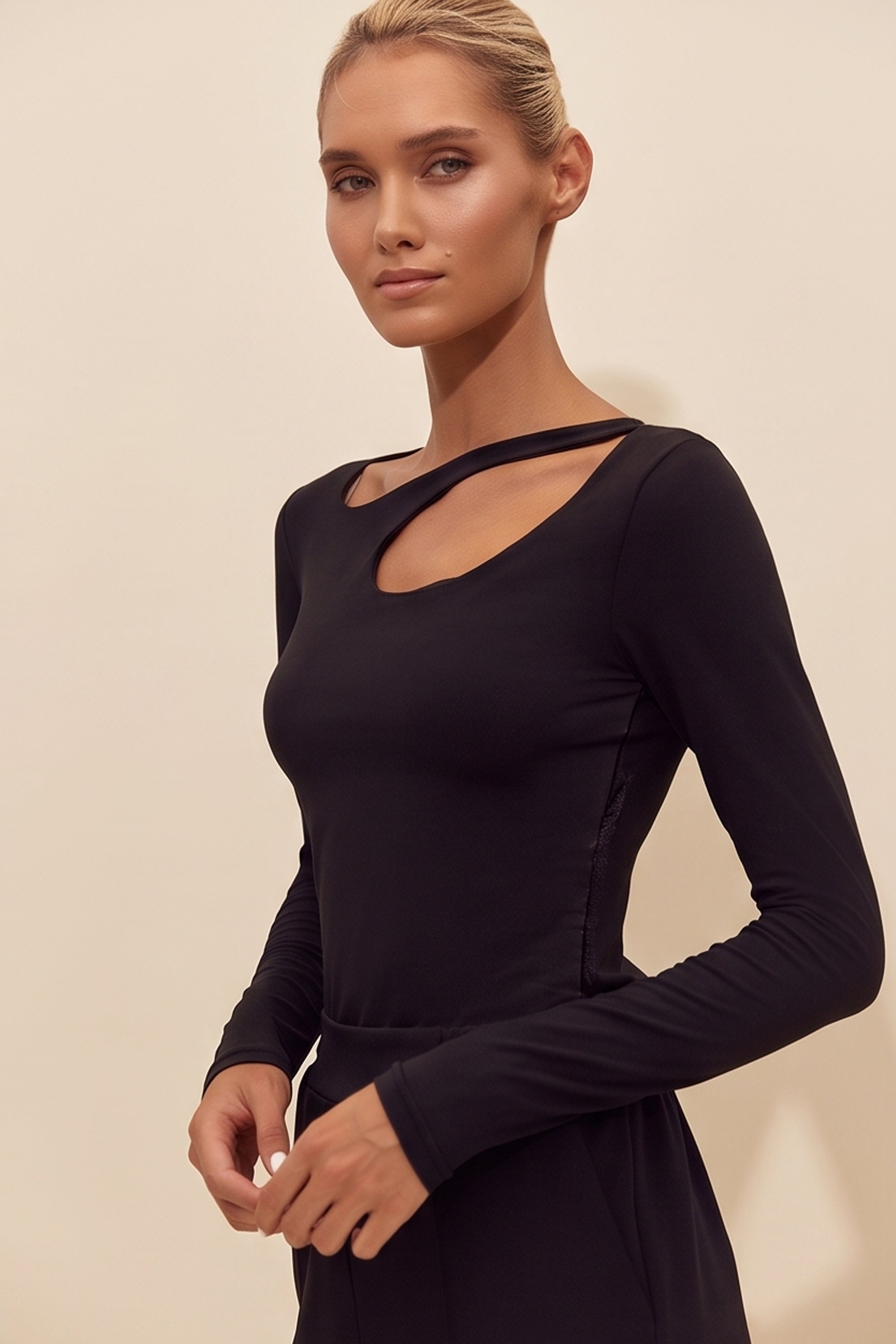Side view of a woman wearing the black Cut Longsleeve top by FemeAdor with fitted silhouette and front cutout detail