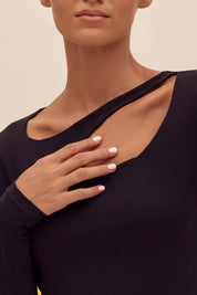 Close up view of a woman wearing the black Cut Longsleeve top by FemeAdor with fitted silhouette and front cutout detail