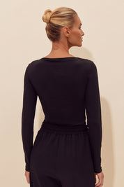 Back view of a woman wearing the black Cut Longsleeve top by FemeAdor with fitted silhouette and front cutout detail