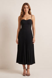 Front view of a woman wearing the black Eclipse Demi Dress by FemeAdor featuring a structured corset top and a flowing pleated midi skirt perfect for formal and casual events