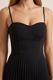 Close up view of a woman wearing the black Eclipse Demi Dress by FemeAdor featuring a structured corset top and a flowing pleated midi skirt perfect for formal and casual events
