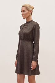 Side view of a woman wearing the black floral mini dress by FemeAdor with delicate floral print, stand-up collar, and flattering fit