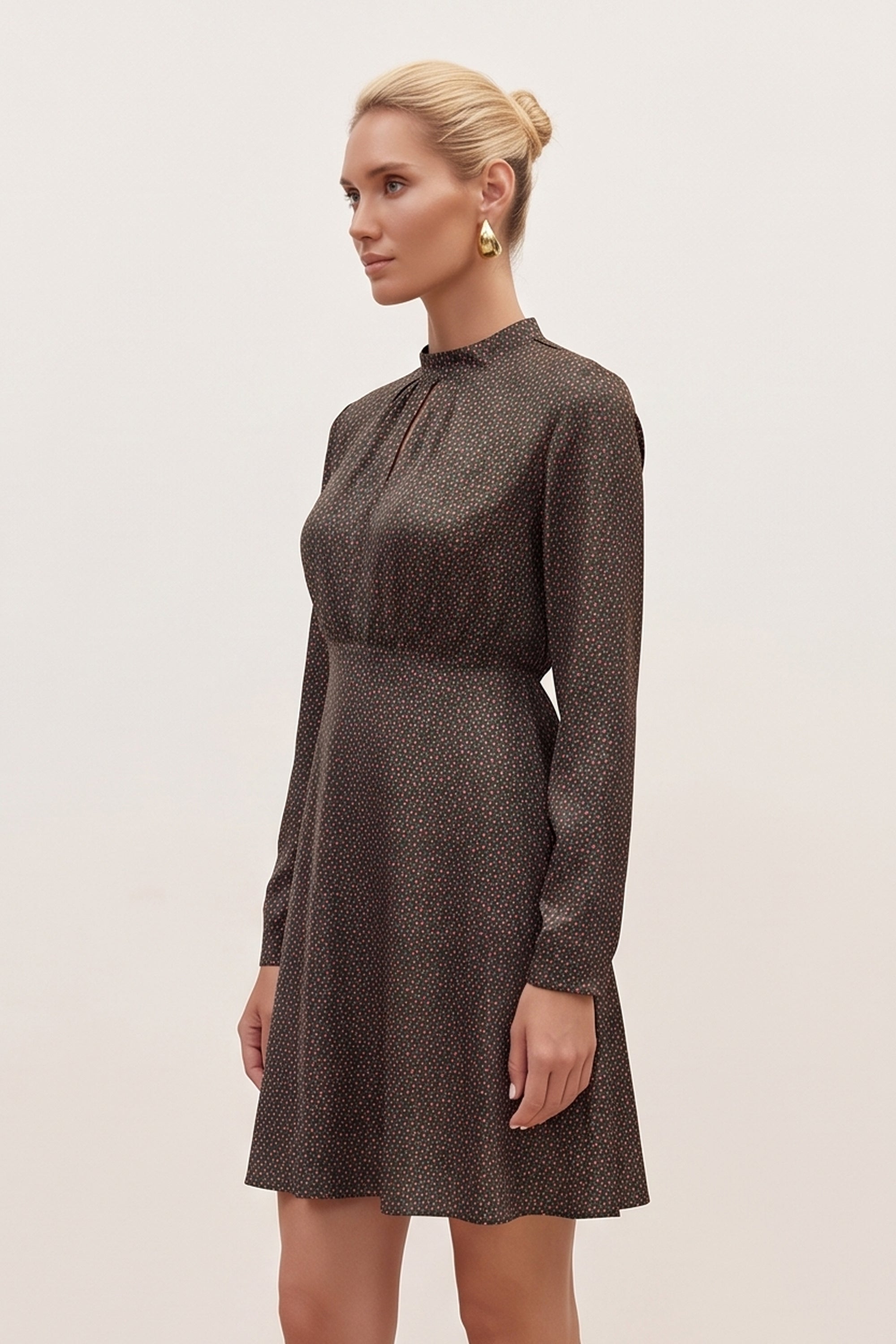 Side view of a woman wearing the black floral mini dress by FemeAdor with delicate floral print, stand-up collar, and flattering fit