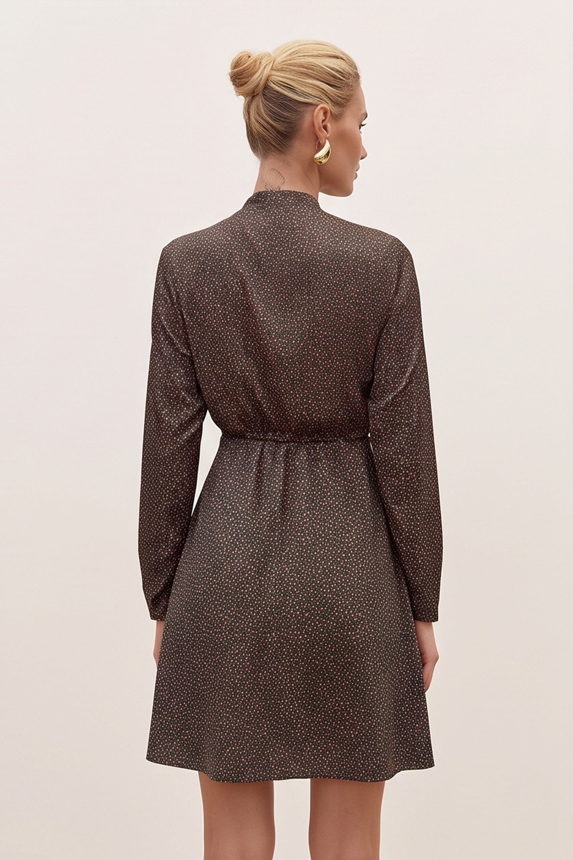 Back view of a woman wearing the black floral mini dress by FemeAdor with delicate floral print, stand-up collar, and flattering fit