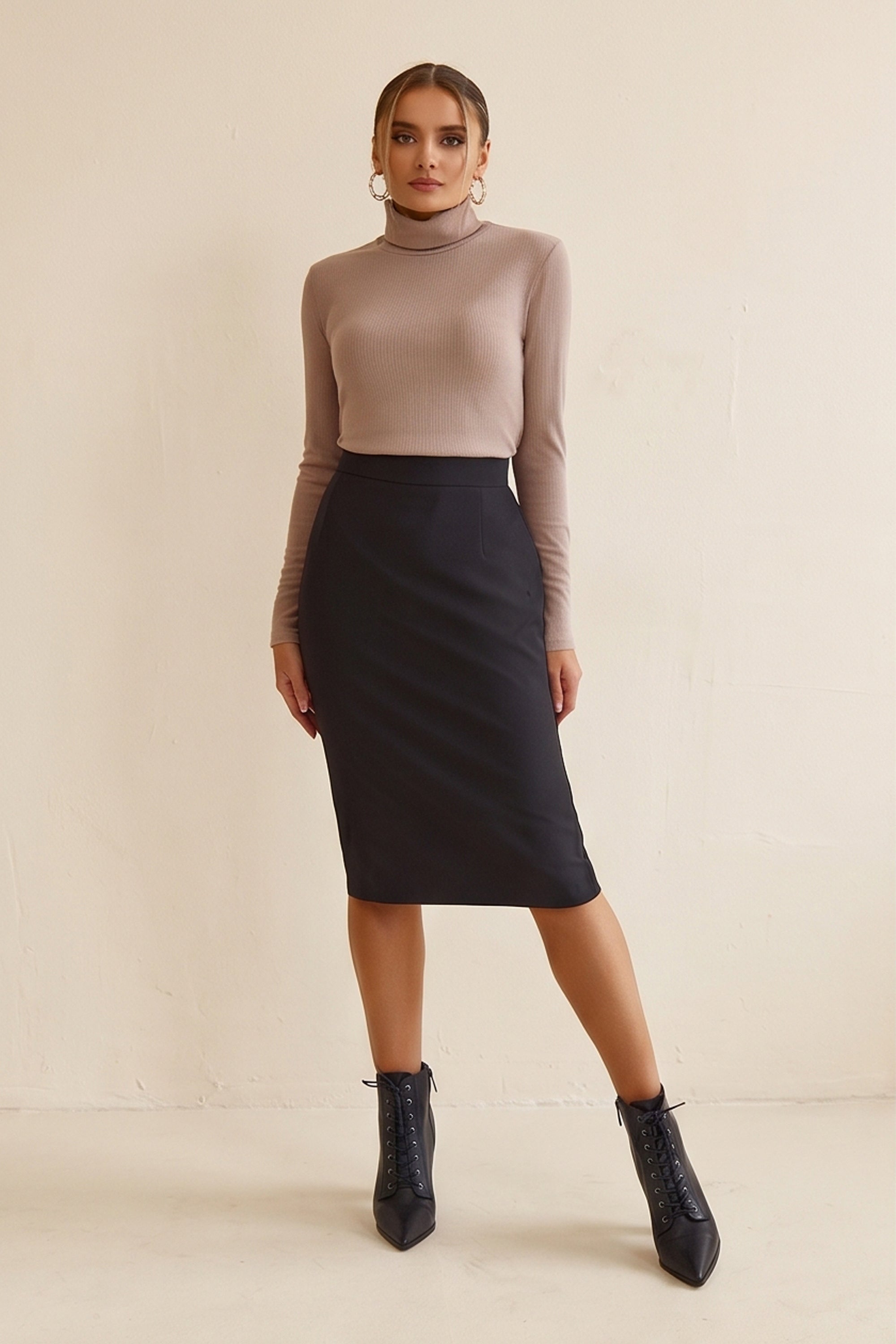 Woman wearing Liaison Skirt by FemeAdor in black featuring a sleek, figure-flattering midi silhouette, ideal for both professional and casual styling