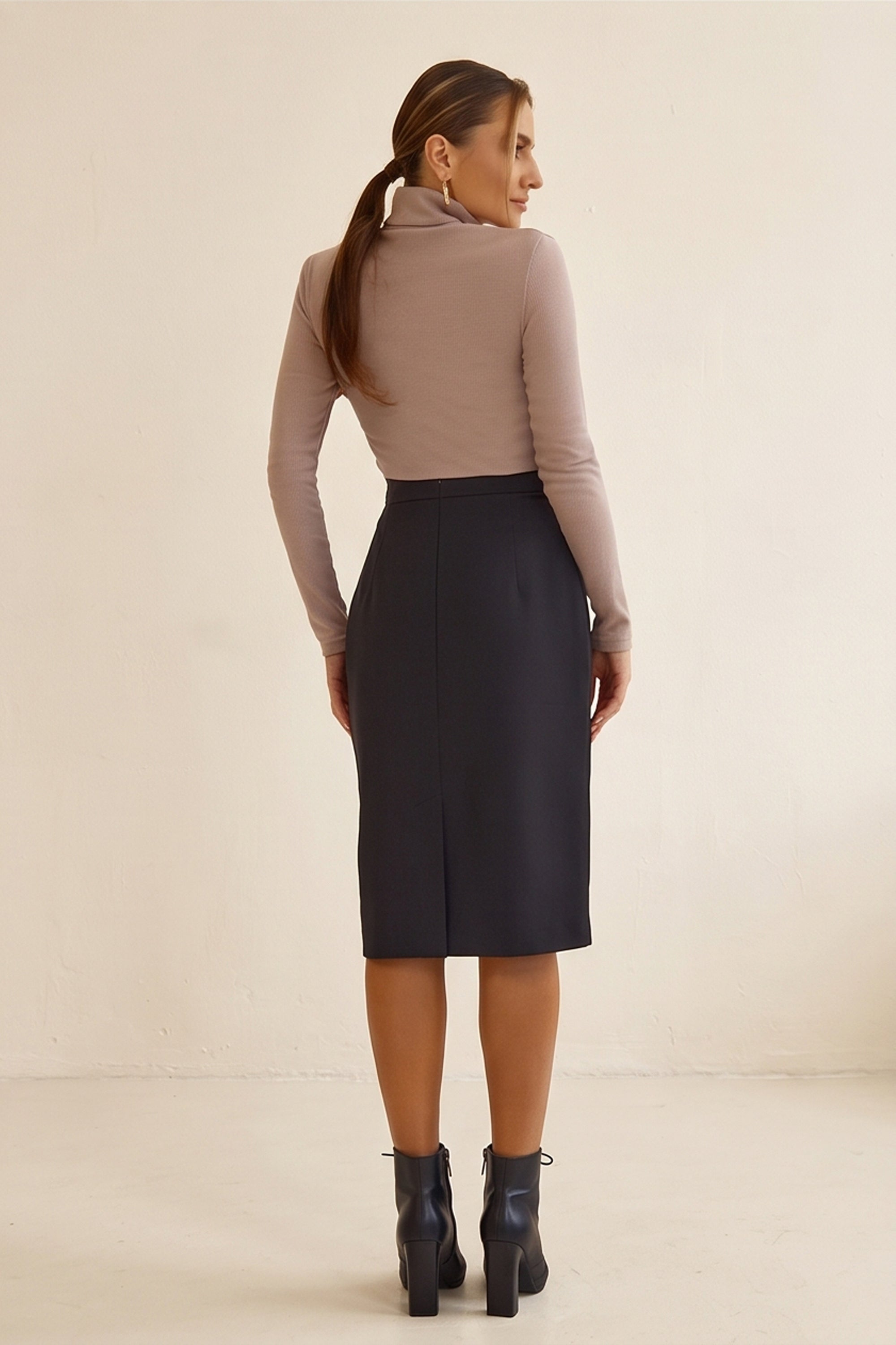 Back view of Liaison Skirt by FemeAdor in black featuring a sleek, figure-flattering midi silhouette, ideal for both professional and casual styling
