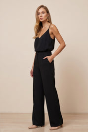 Side view of a woman wearing black Moda Trousers by FemeAdor featuring a high-waisted, wide-leg tailored fit for modern styling