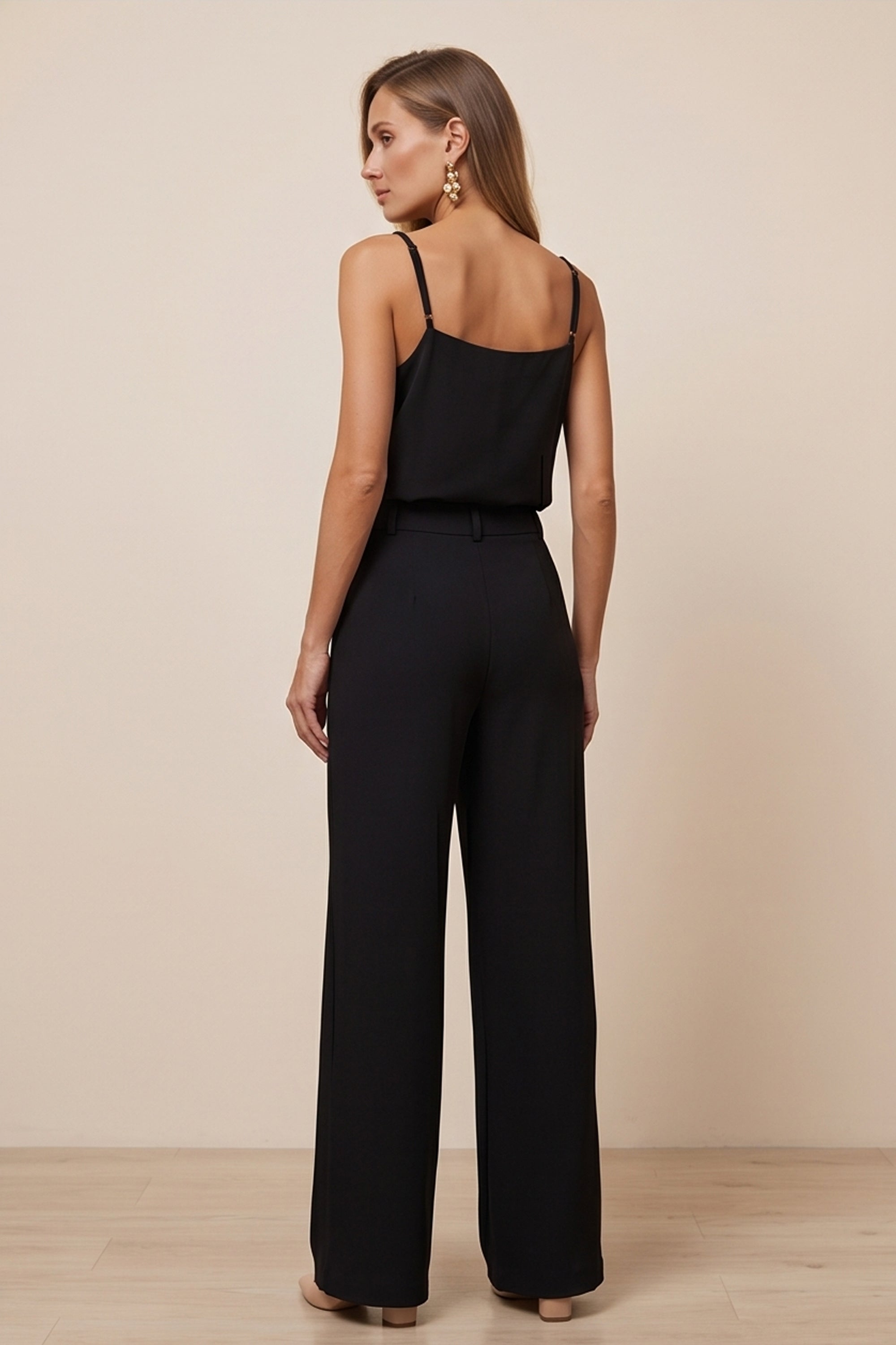 Back view of a woman wearing black Moda Trousers by FemeAdor featuring a high-waisted, wide-leg tailored fit for modern styling