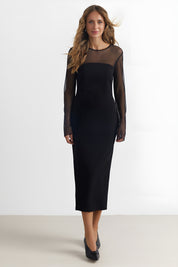 Front view of a woman wearing the black noir midi dress by FemeAdor featuring a sheath silhouette and sheer front insert for an elegant, modern look