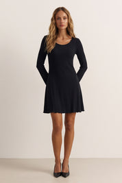 Front view of a woman wearing the black Velora Mini Dress by FemeAdor with long sleeves featuring a ribbed design and flattering fit for casual or evening wear