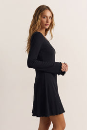 Side view of a woman wearing the black Velora Mini Dress by FemeAdor with long sleeves featuring a ribbed design and flattering fit for casual or evening wear