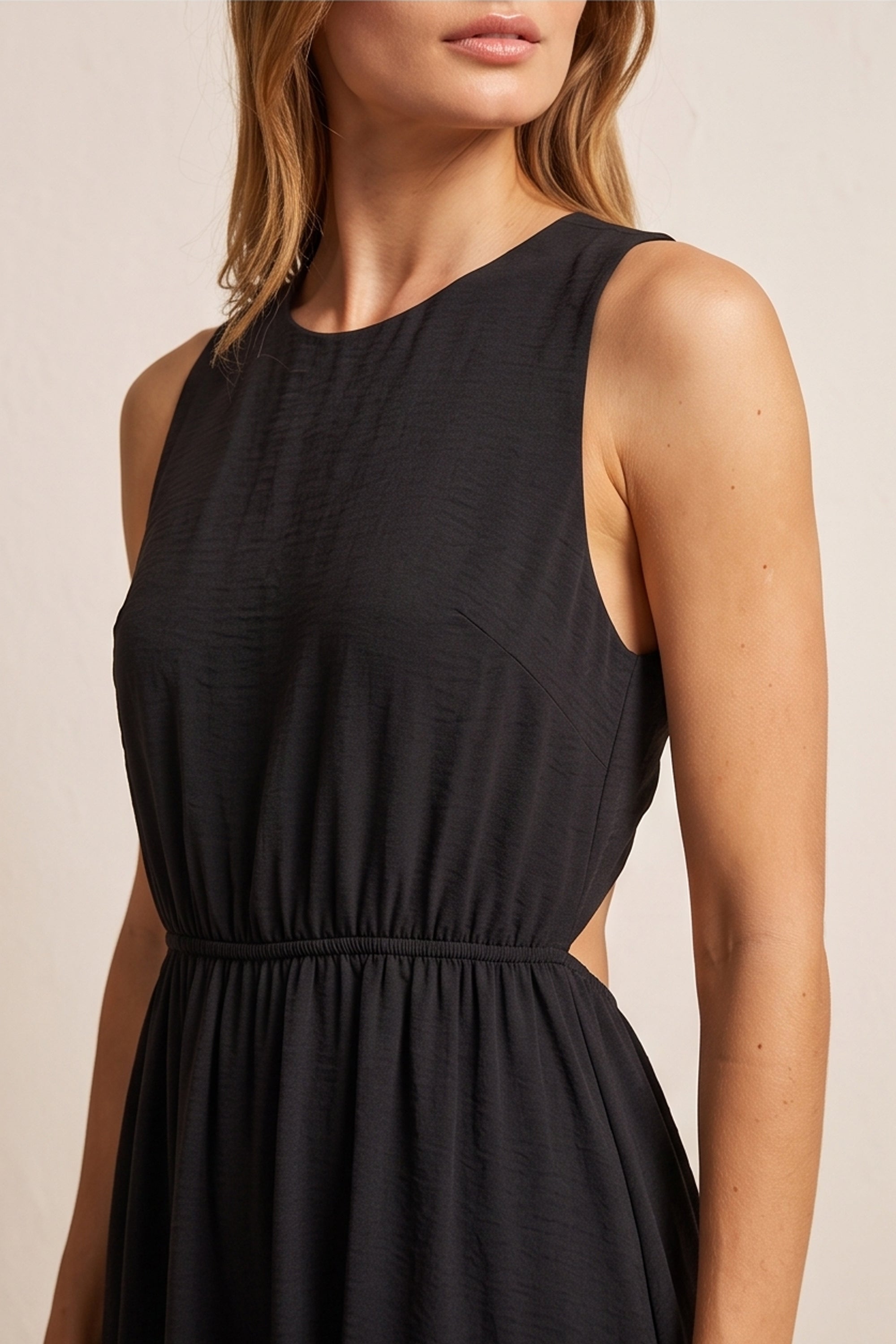 Close up view of a woman wearing the black Virella Maxi Dress with sleeveless design, open back, and floor-length silhouette for elegant evening wear