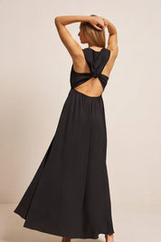 Back view of a woman wearing the black Virella Maxi Dress with sleeveless design, open back, and floor-length silhouette for elegant evening wear