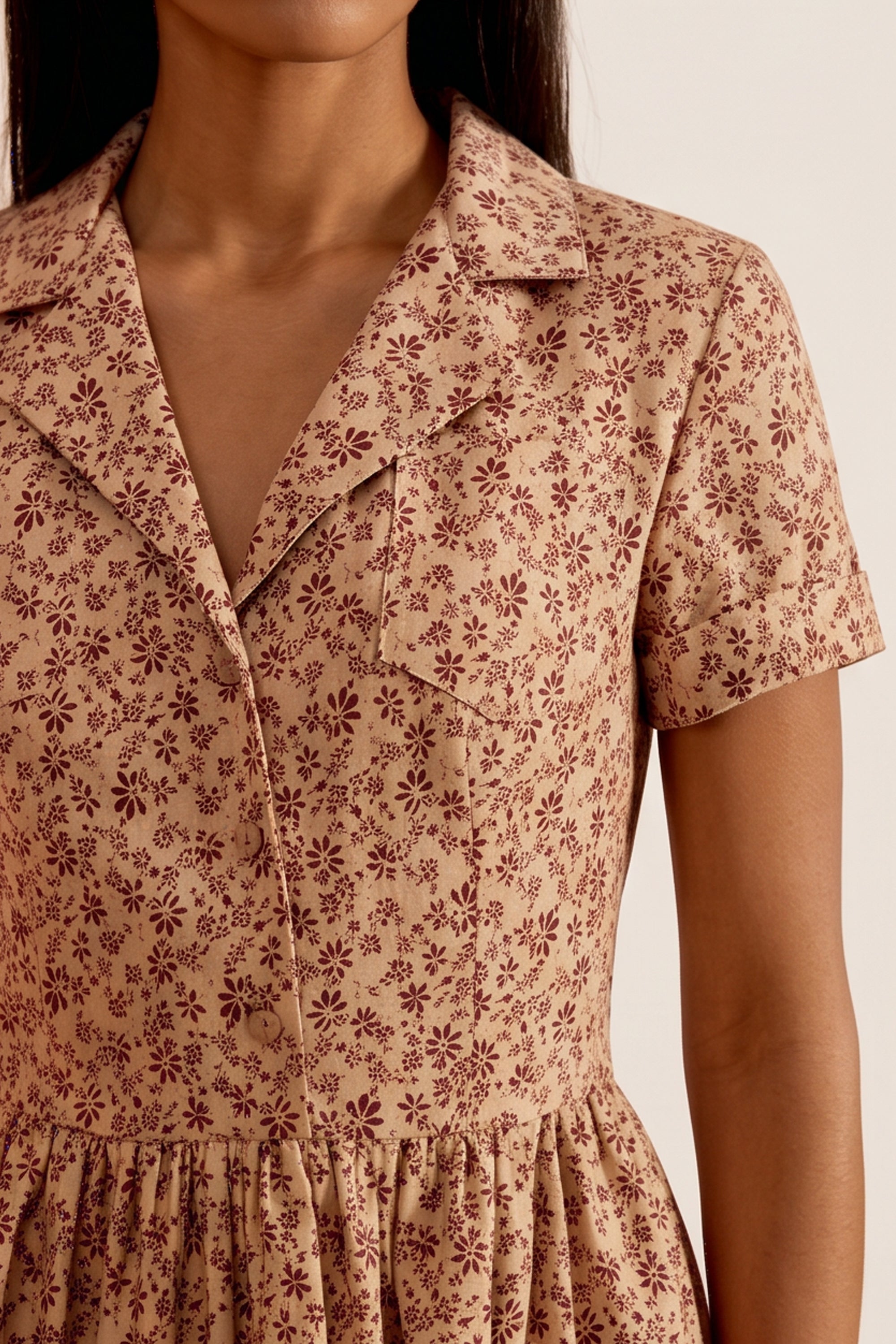Close up view of a woman wearing the brown Mocha Mini Dress in floral linen with short sleeves and collared neck design by FemeAdor