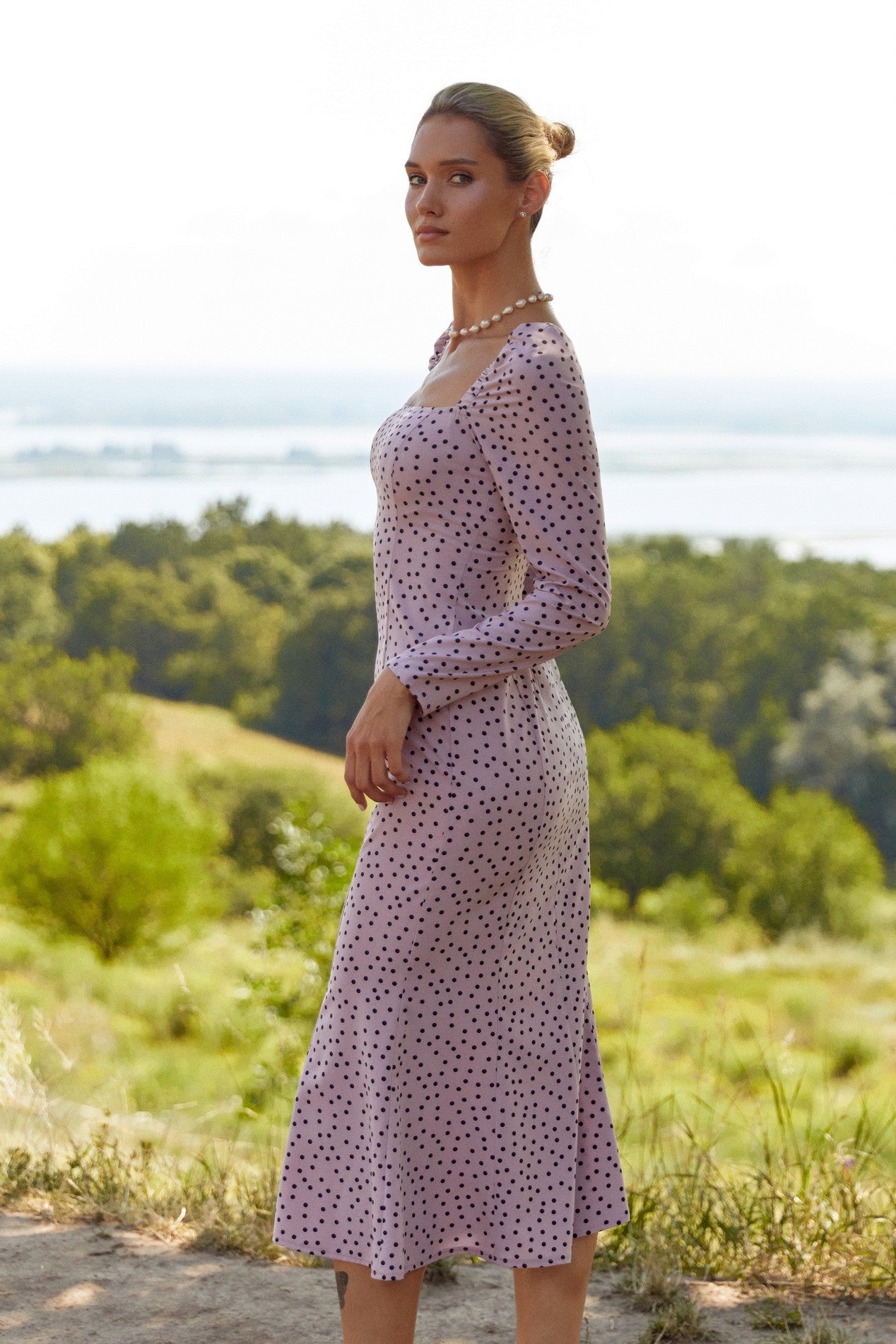 Side view of the Celestra Midi Dress by FemeAdor in pink featuring a flattering fit-and-flare silhouette and timeless polka dot pattern