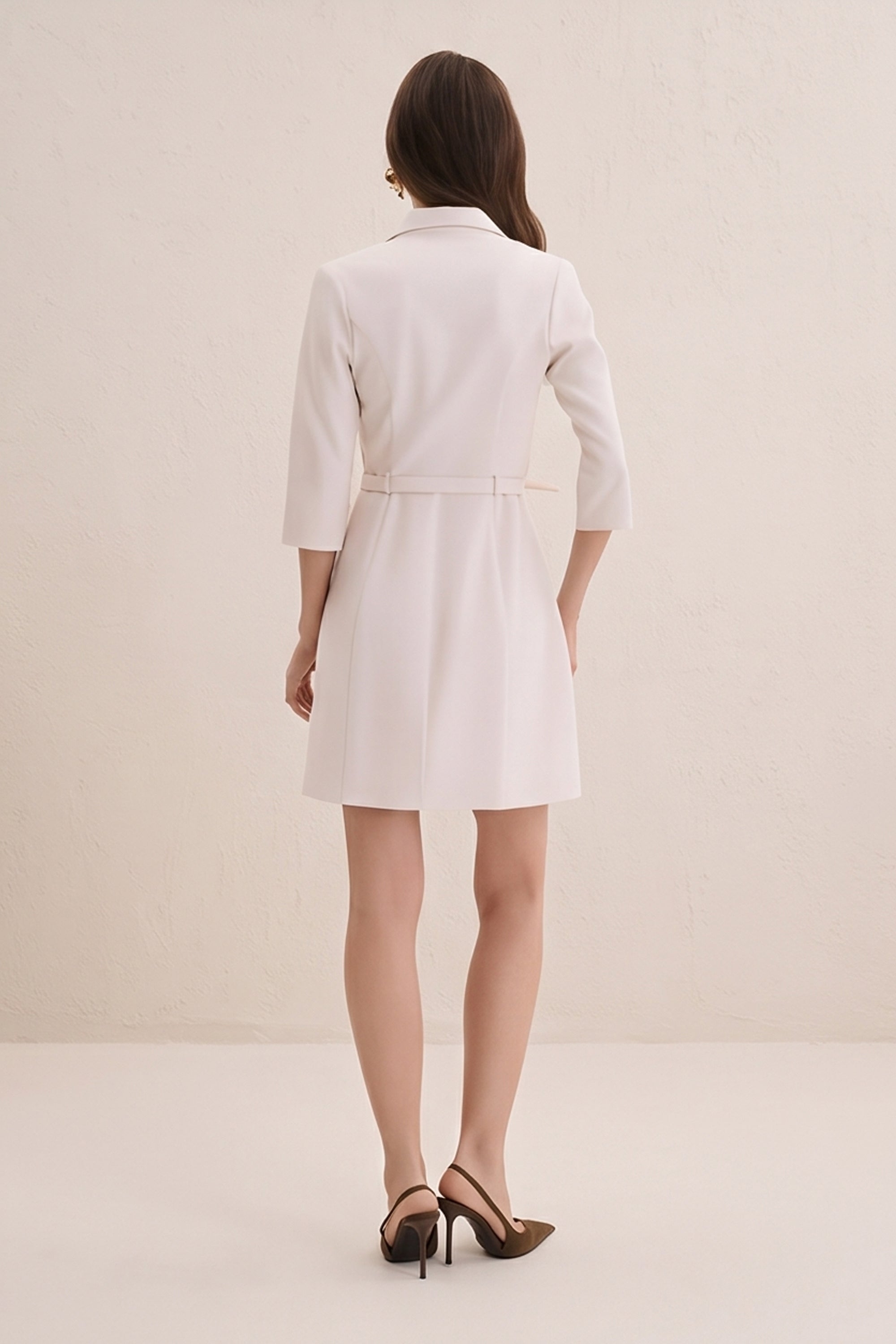 Back view of a woman wearing the cream vespera mini dress-jacket by FemeAdor
