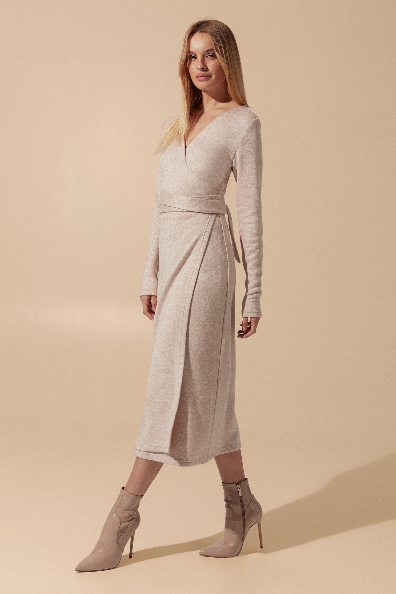 Slight side view of the Emberlyn Midi Dress in beige angora fabric with longsleeves and wrap around belt