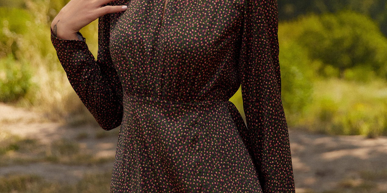 Front view of a woman wearing the floral mini dress by FemeAdor in black with delicate floral print, stand-up collar, and flattering fit