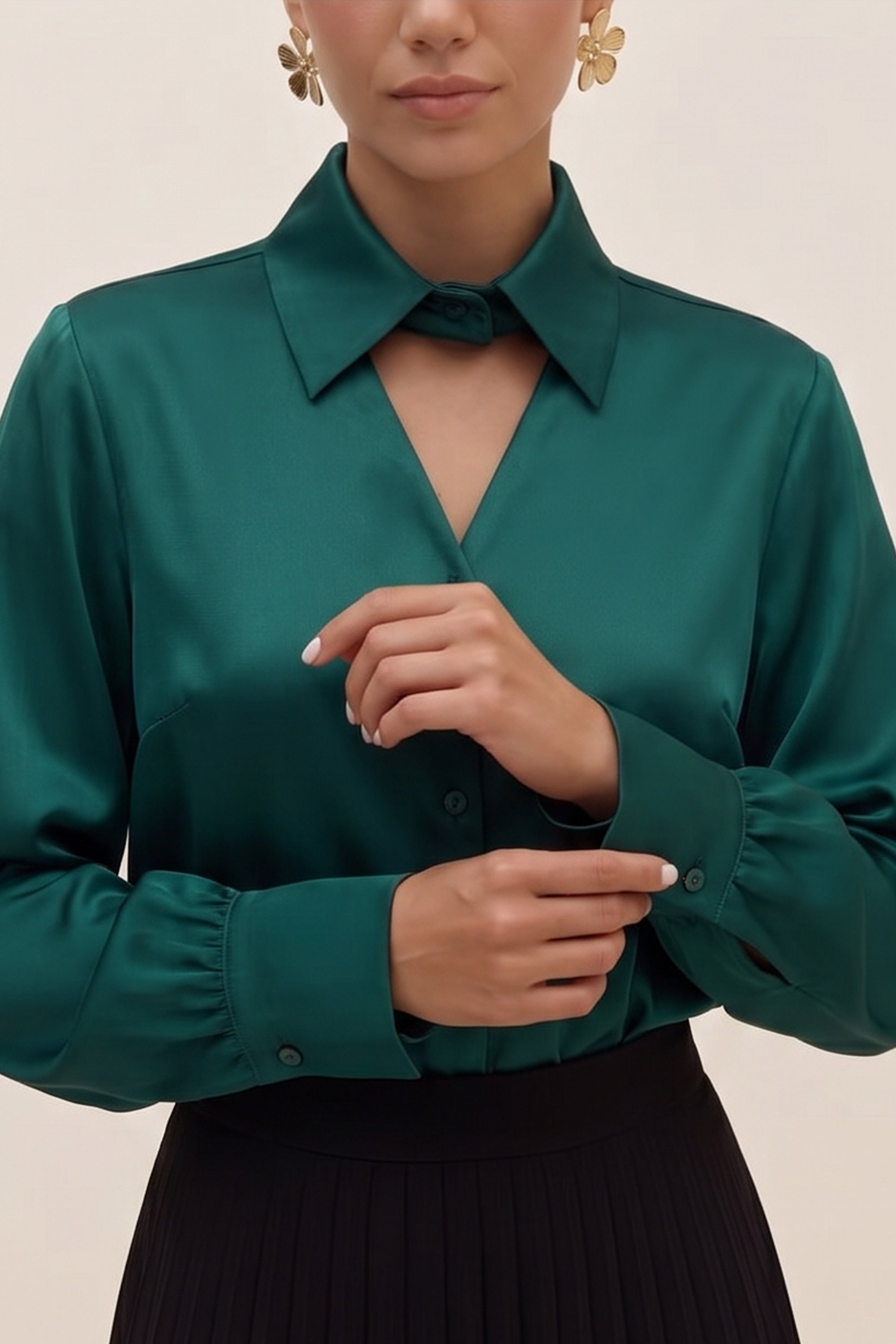 Close up view of a woman wearing a silk like green eminence blouse by femeador and black skirt against a beige background