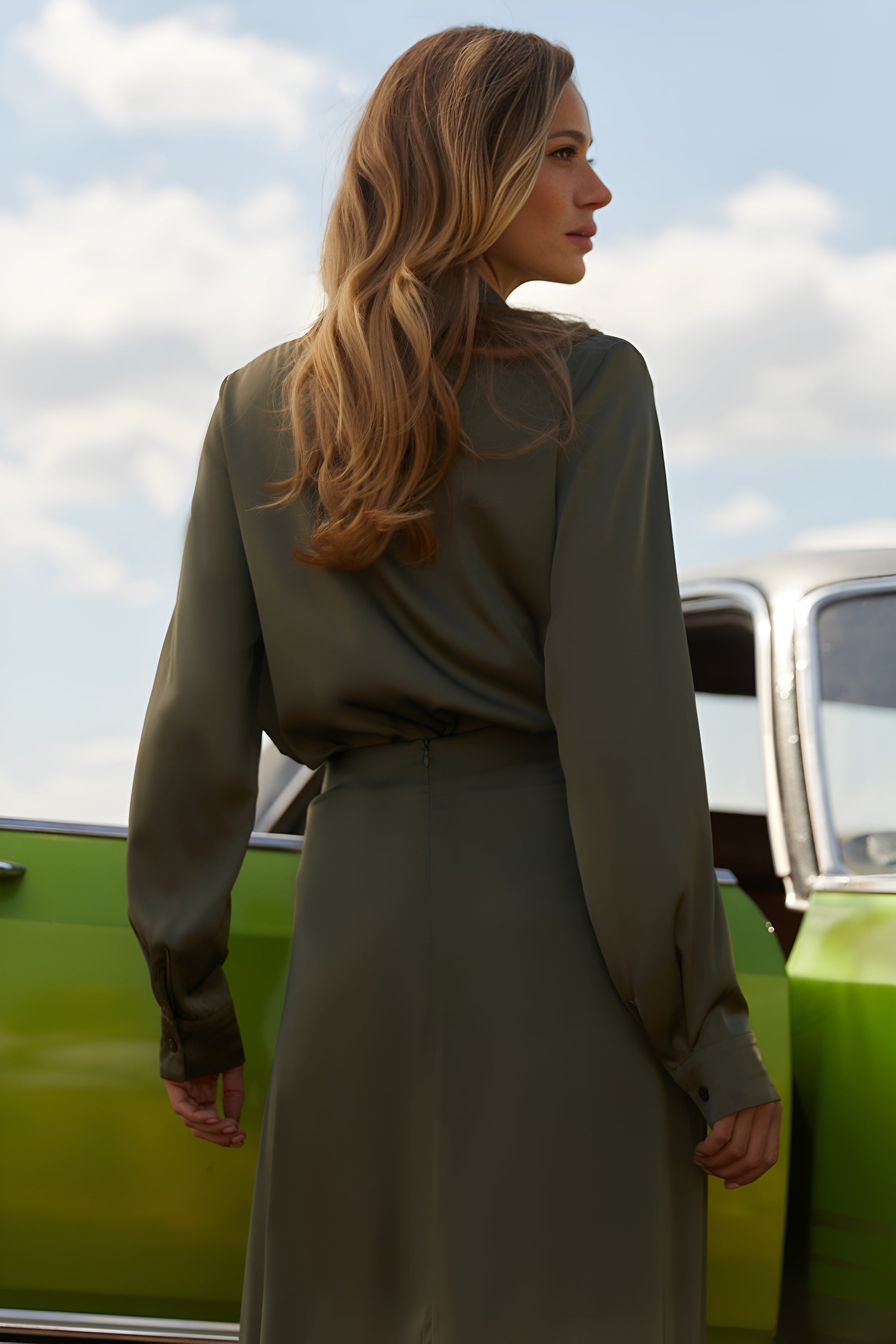 Back view of a woman wearing the Nora Blouse in green satin with silk-like sheen and flattering drape, perfect for work or special occasions
