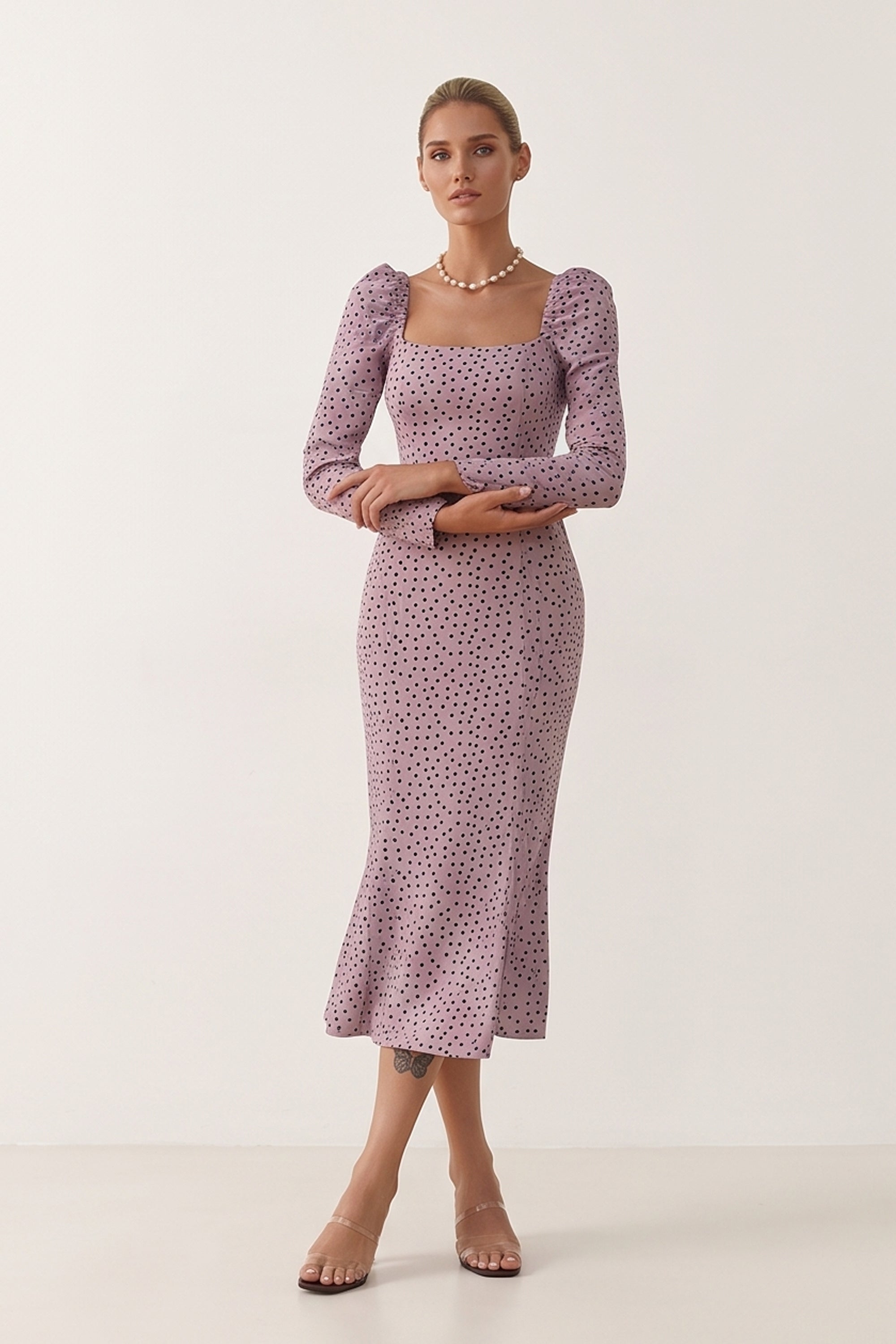 Front view of a woman wearing the pink Celestra Midi Dress by FemeAdor featuring a flattering fit-and-flare silhouette and timeless polka dot pattern