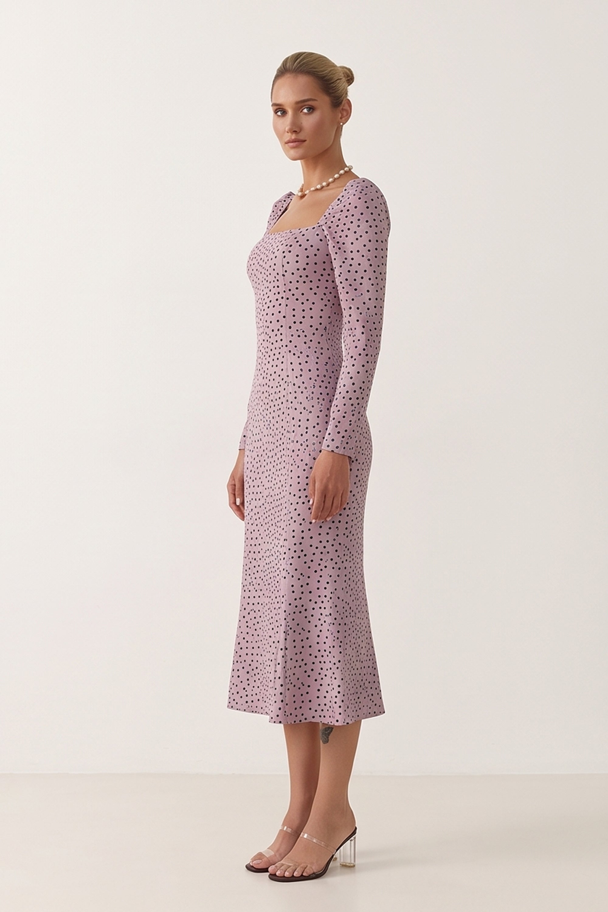 Side view of a woman wearing the pink Celestra Midi Dress by FemeAdor featuring a flattering fit-and-flare silhouette and timeless polka dot pattern