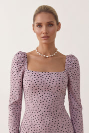 Close up view of a woman wearing the pink Celestra Midi Dress by FemeAdor featuring a flattering fit-and-flare silhouette and timeless polka dot pattern