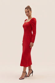Side view of a woman wearing the red Celestra Midi Dress by FemeAdor featuring a flattering fit-and-flare silhouette and timeless polka dot pattern