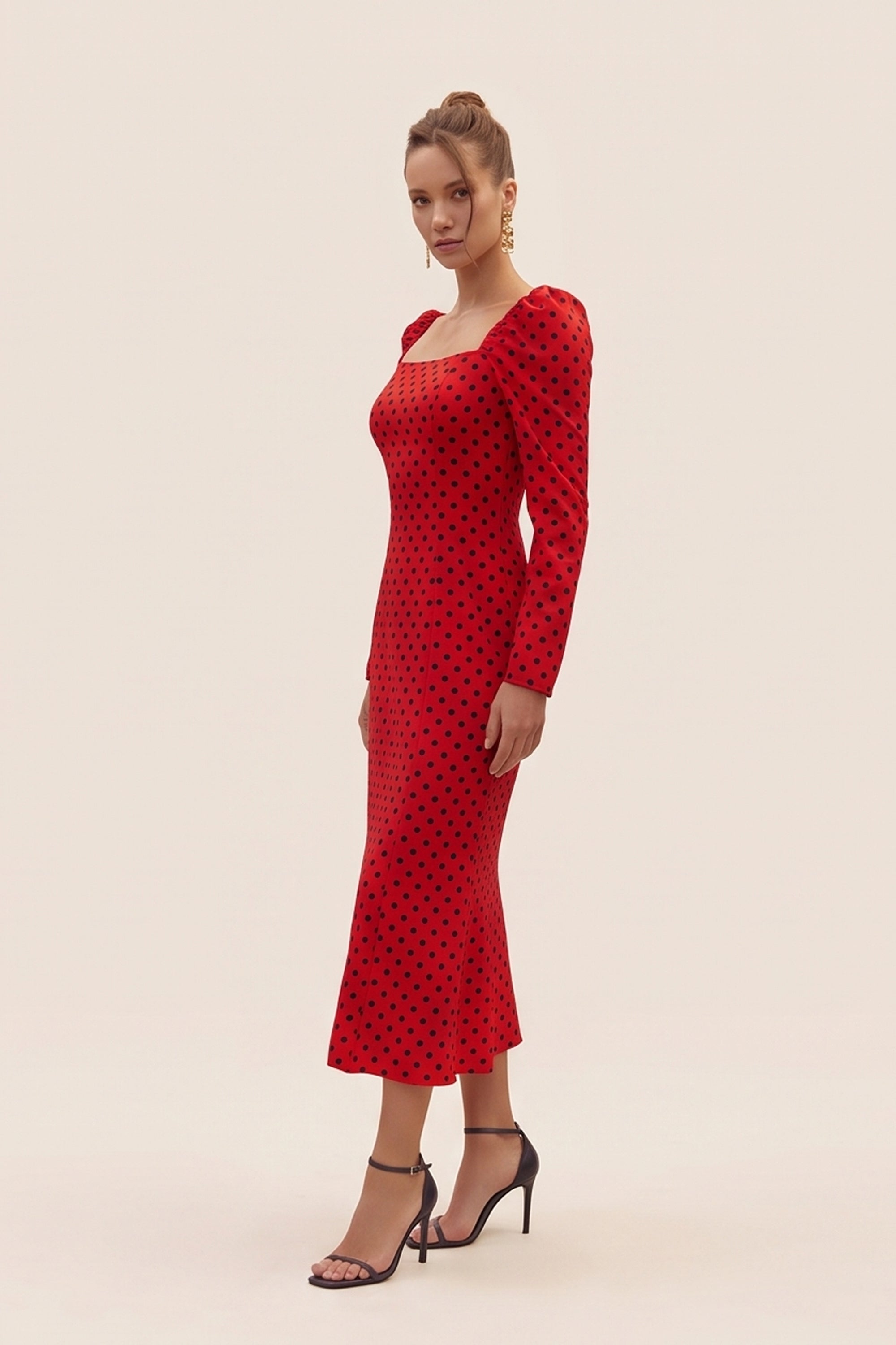 Side view of a woman wearing the red Celestra Midi Dress by FemeAdor featuring a flattering fit-and-flare silhouette and timeless polka dot pattern