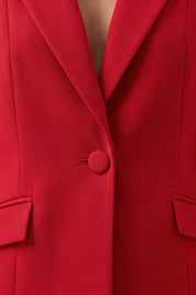 A woman shown from the close up wearing a bright red tailored blazer