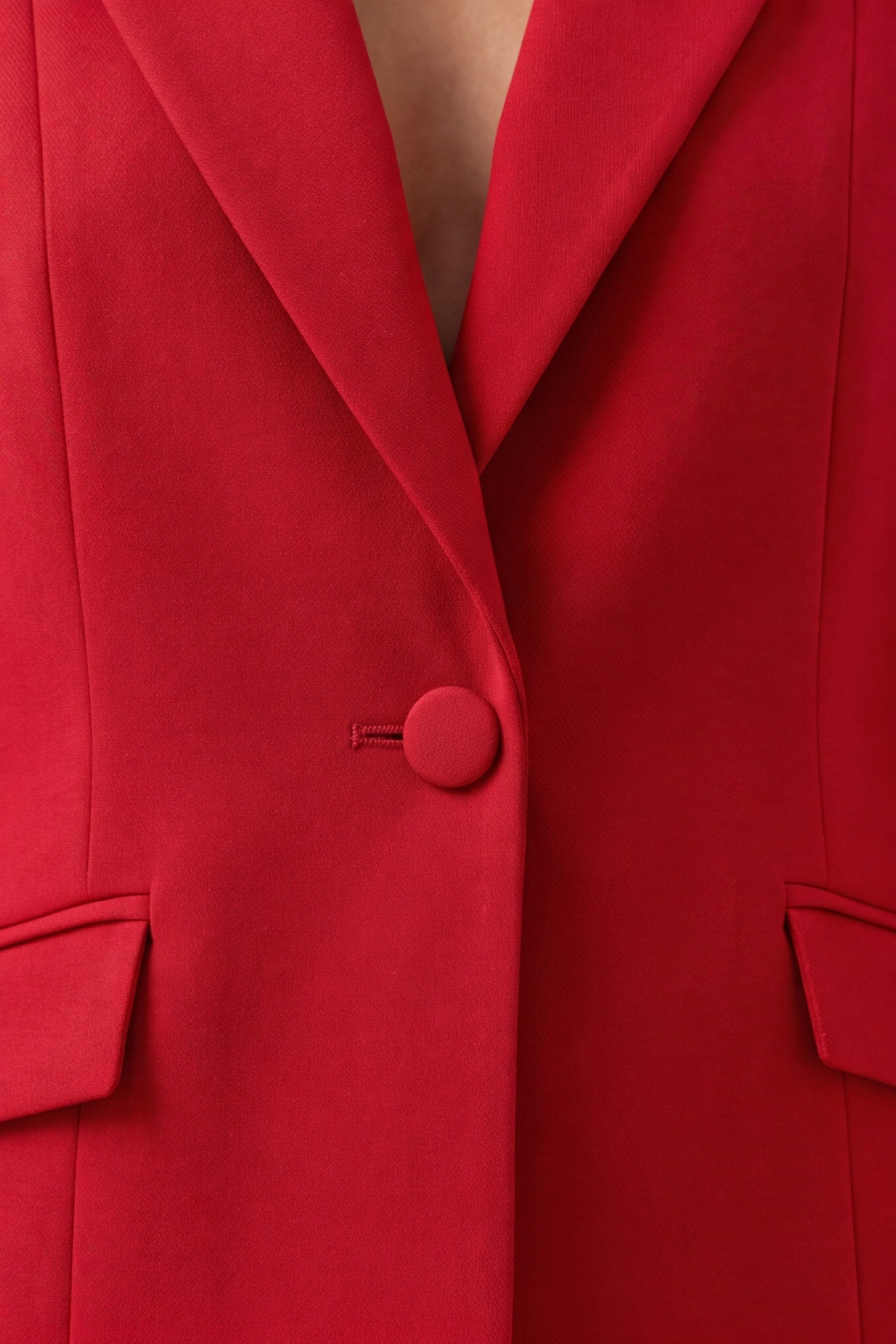 A woman shown from the close up wearing a bright red tailored blazer