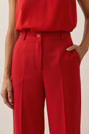 Close up view of a woman wearing red Moda suit pants by FemeAdor featuring a high-waisted, wide-leg tailored fit for modern styling