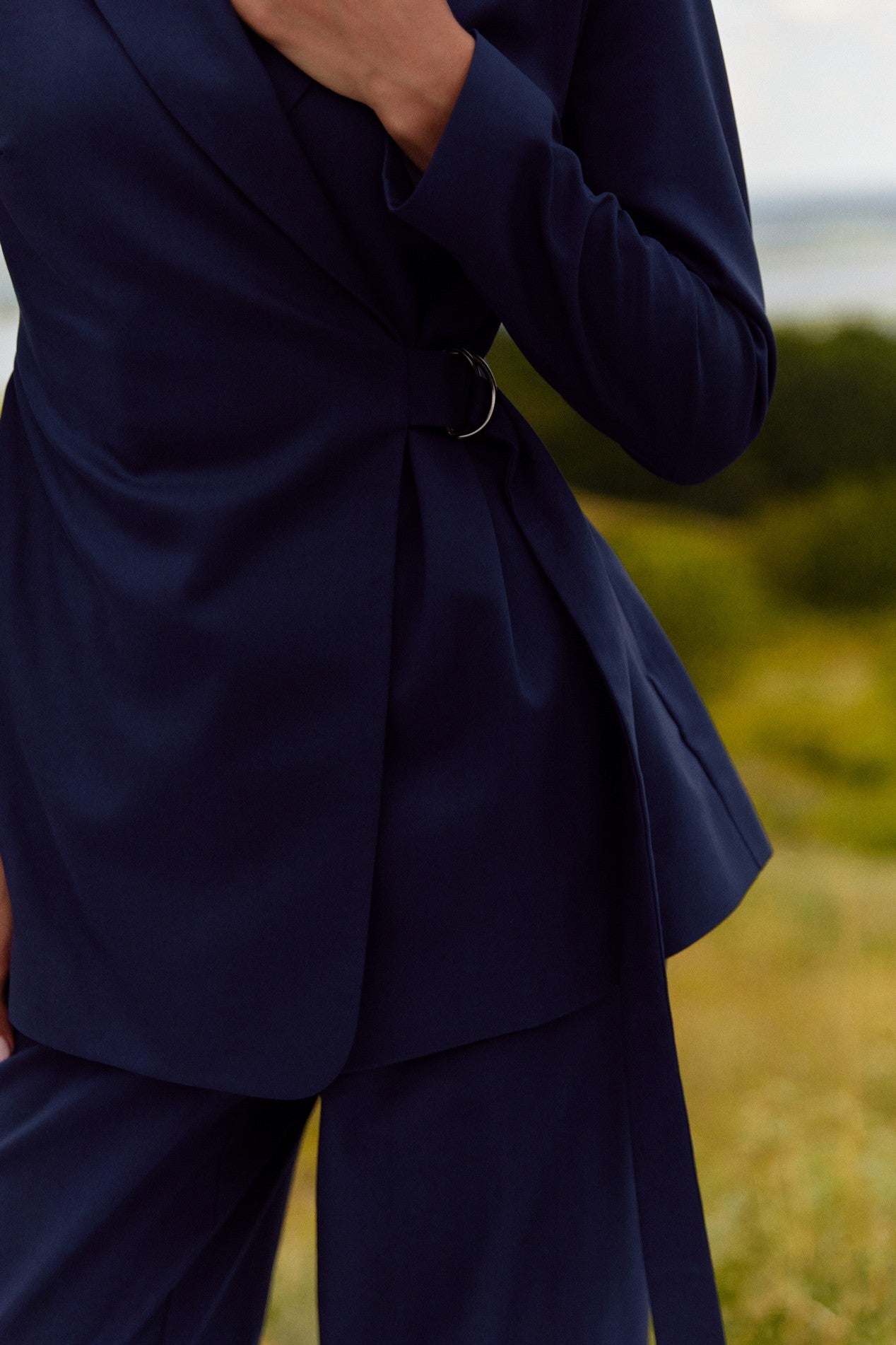 Close up of Regal Blazer by FemeAdor in navy blue featuring a tailored belted silhouette, ideal for professional and casual styling