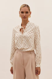 Front view of a woman wearing the white Floral Blouse by FemeAdor featuring a delicate floral print and tie detail, perfect for casual or polished looks