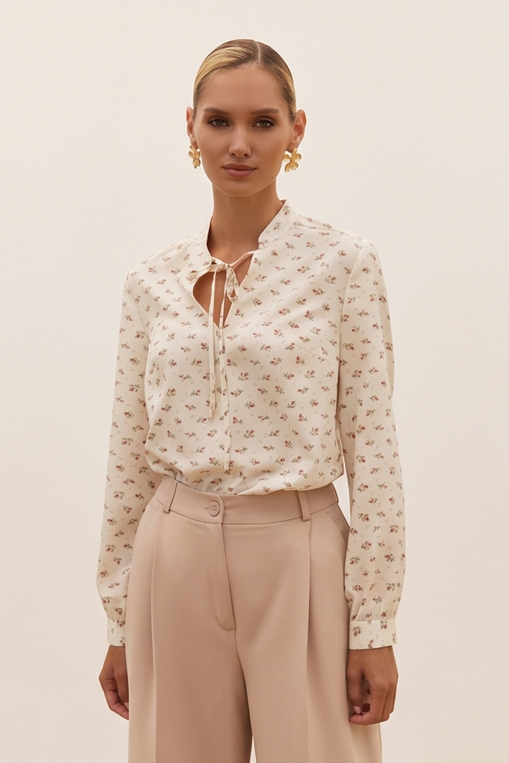 Front view of a woman wearing the white Floral Blouse by FemeAdor featuring a delicate floral print and tie detail, perfect for casual or polished looks