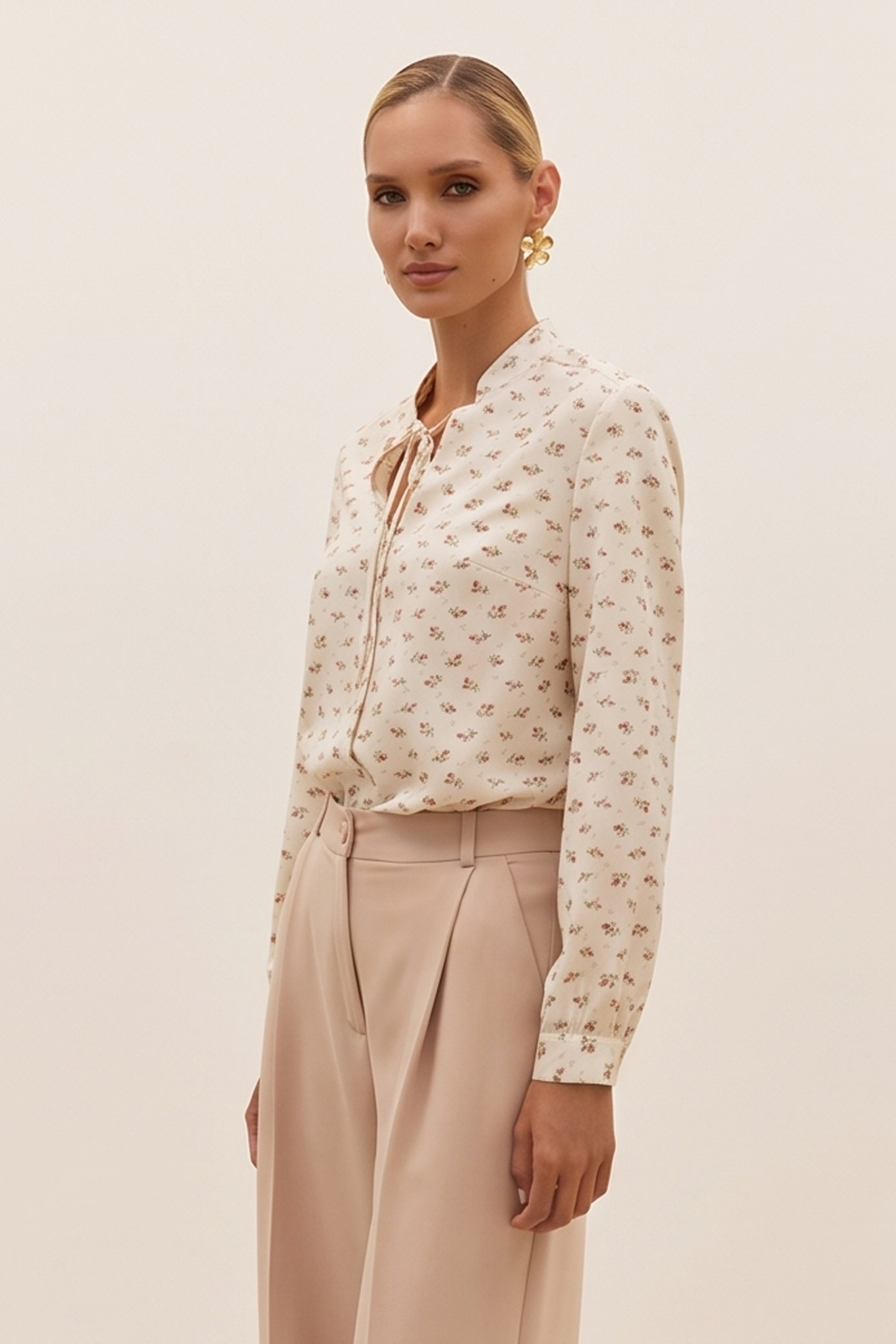 Side view of a woman wearing the white Floral Blouse by FemeAdor featuring a delicate floral print and tie detail, perfect for casual or polished looks